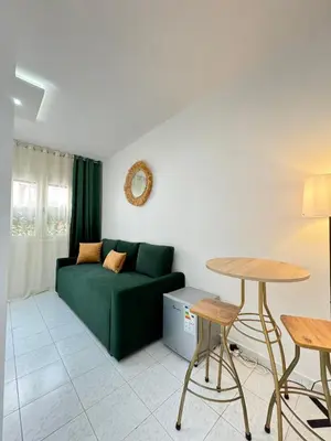 a living room with a green couch and a table at SUITOUISS - Agdal - Studio en plein cœur de Rabat à 5 minutes du grand mall Arribat Center - centre ville in Rabat