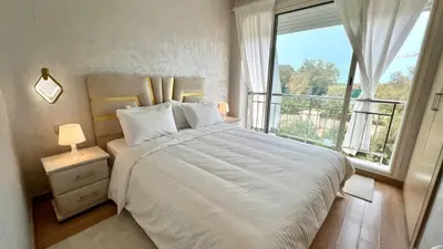 a bedroom with a large white bed and a window at Prestigia Hay Riad, Appartement Moderne au Style Chic in Rabat