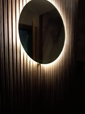 a round mirror hanging on a wall with wooden panels at Relax toute l'année Piscine chauffée in Temara
