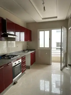 an empty kitchen with red cabinets and a stove at Ait Ali in Casablanca