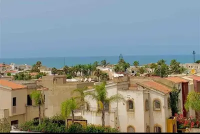 a city with buildings and palm trees and the ocean at Paradis Avec Vue Harhoura in El Harhoura