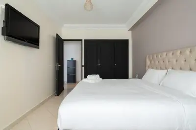 a bedroom with a white bed and a flat screen tv at Appartement Spacieux a Maarif in Casablanca