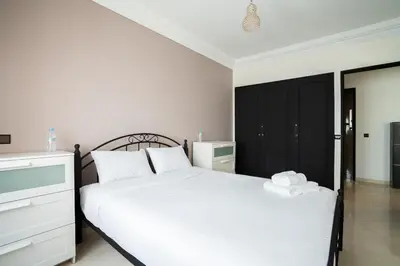 a bedroom with a white bed and a black cabinet at Appartement Spacieux a Maarif in Casablanca