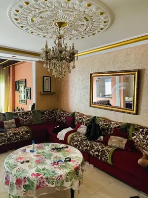 a living room with a red couch and a chandelier at harhoura Résidence Badia in Temara