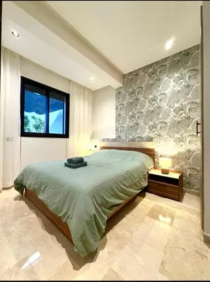 a bedroom with a large bed and a stone wall at Casablanca Maarif Extension Green Retreat in Casablanca