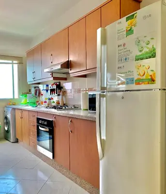 a kitchen with a white refrigerator and wooden cabinets at Paradis Avec Piscine et Vue sur mer Harhoura in Temara