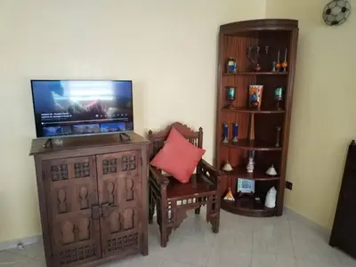 a living room with a television and a chair with a red pillow at Paradis Avec Piscine et Vue sur mer Harhoura in Temara