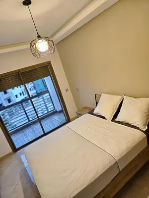 a bedroom with a bed and a large window at Grand appartement vue sur piscine Bouznika in Kasba Bou Hamira