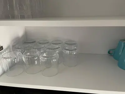 a group of clear cups sitting on a counter at Grand appartement vue sur piscine Bouznika in Kasba Bou Hamira