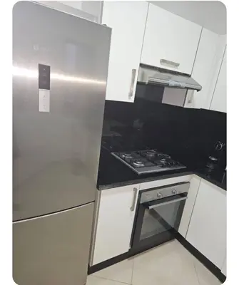 a kitchen with a stove and a refrigerator at Grand appartement vue sur piscine Bouznika in Kasba Bou Hamira