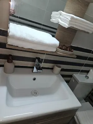 a bathroom with a white sink and towels at Grand appartement vue sur piscine Bouznika in Kasba Bou Hamira