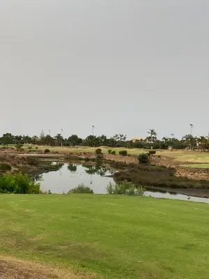 a pond in the middle of a field with green grass at Grand appartement vue sur piscine Bouznika in Kasba Bou Hamira