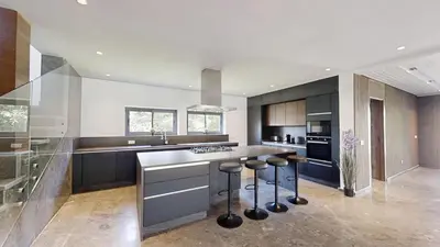 a large kitchen with a counter and stools in it at Villa S- Luxurious 8 masterbedrooms villa on 3000m2, close to all amenities, Golf and heart of Souissi in Rabat