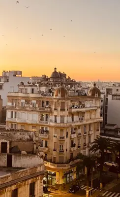 a building in a city with a sunset in the background at Loft art-déco centre-ville Casa in Casablanca