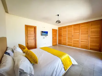 a bedroom with a large white bed with yellow pillows at Villa de luxe résidence front de mer 50m de la mer in Tamaris