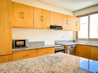 a kitchen with wooden cabinets and a counter top at Villa de luxe résidence front de mer 50m de la mer in Tamaris