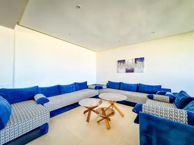 a living room with blue couches and two tables at Villa de luxe résidence front de mer 50m de la mer in Tamaris