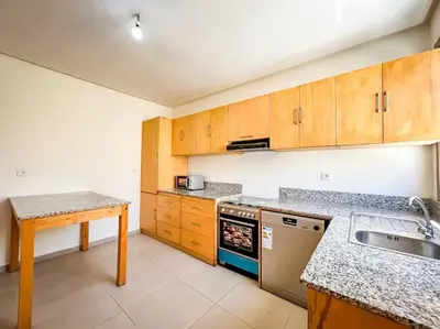 a kitchen with wooden cabinets and a sink and a table at Villa de luxe résidence front de mer 50m de la mer in Tamaris