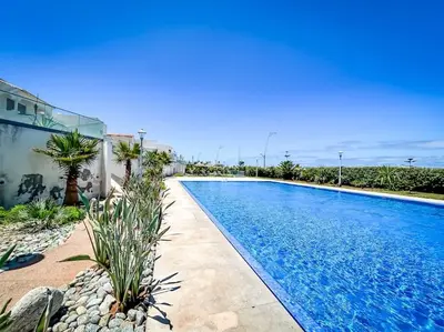a swimming pool with palm trees next to a building at Villa de luxe résidence front de mer 50m de la mer in Tamaris