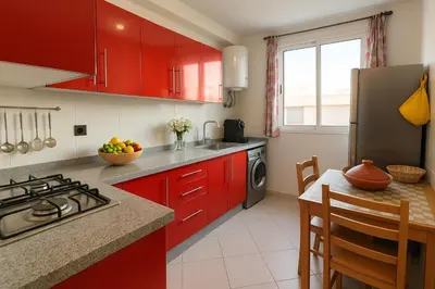 a kitchen with red cabinets and a counter top at Cosy ensoleillé 3 CH - central et proche du train et tramway in Casablanca