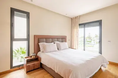 a bedroom with a large bed and two windows at Sojori CFC fibre et parking in Casablanca