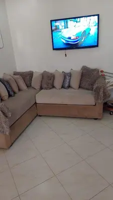 a couch in a living room with a tv on the wall at Sweet home in Dar Bouazza