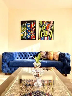 a living room with a blue couch and some paintings at Appartement en résidence privée in Casablanca