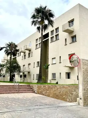 a building with a palm tree in front of it at Appartement en résidence privée in Casablanca
