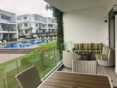 a balcony with chairs and a view of a pool at Moroccan Beach Delight in Dar Bouazza