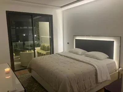 a bedroom with a large bed and a living room at Moroccan Beach Delight in Dar Bouazza