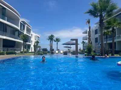a group of people in a swimming pool with palm trees at Moroccan Beach Delight in Dar Bouazza
