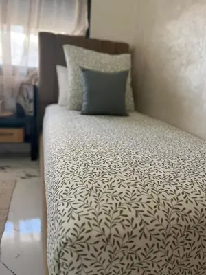a bed with a black and white comforter and a pillow at Cosy appartement lumineux Awards 2026 in Bouznika