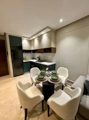 a living room with a table and chairs and a kitchen at Studio Lilas CFC in Casablanca