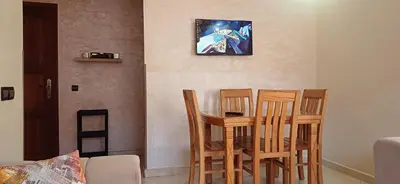 a room with three chairs and a table with a clock on the wall at Appartement très propre et calme in Bouznika