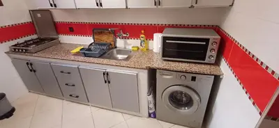 a small kitchen with a sink and a washing machine at Appartement très propre et calme in Bouznika