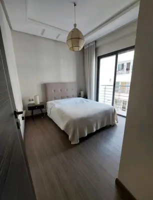 a white bedroom with a bed and a large window at Downtown apartment in Casablanca