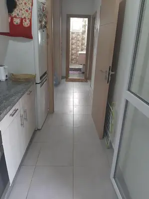 a kitchen with white cabinets and a white tile floor at Espace de détente in Bouznika