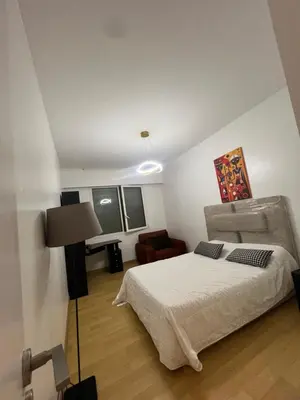 a white bedroom with a bed and a chair at Magnifique appartement maarif in Casablanca
