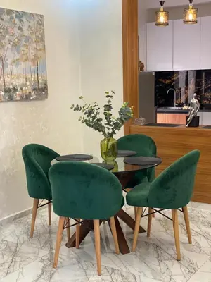 a table with four green chairs and a vase on it at Bel appartement de plage - RDC - Dahomey Beach in Bouznika