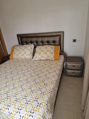 a bed with two pillows and a nightstand at 2 bedroom appart at the beach in gated community with pool in Sidi Rahal