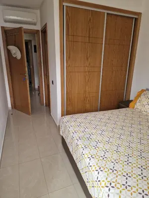 a bedroom with a bed and a wooden closet at 2 bedroom appart at the beach in gated community with pool in Sidi Rahal