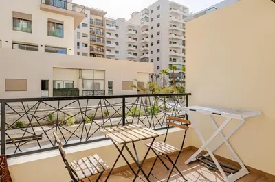 a balcony with a table and chairs and buildings at Studio Élégant avec piscine à Zenata Eco city in Aïn Harrouda
