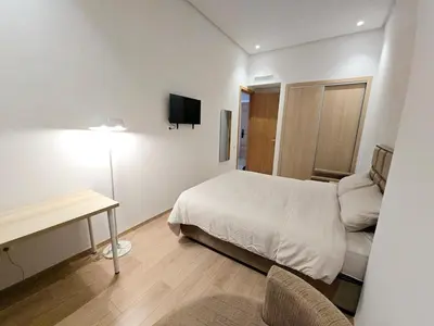 a bedroom with a bed and a desk and a television at Studio Élégant avec piscine à Zenata Eco city in Aïn Harrouda