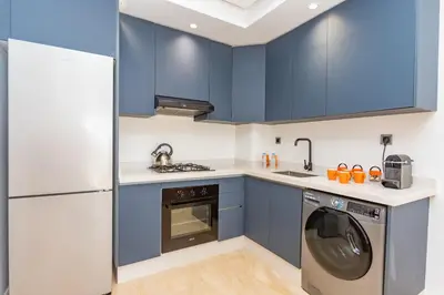 a kitchen with blue cabinets and a washer and dryer at Welcome Home Palmiers in Casablanca