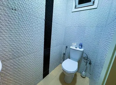 a bathroom with a toilet and a tiled wall at très joli appartement vue sur mer présentation acte de mariage si couple in Rabat
