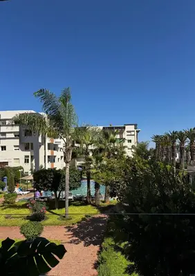 a park with palm trees in front of a building at L Évasion ZEN Duplex d Exception Entre Plage et Serenite in Mohammedia