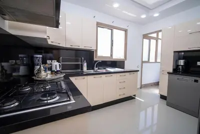 a kitchen with white cabinets and black counter tops at Welcome to Casa Luxe 3 King Beds Near CFC & Tram in Casablanca