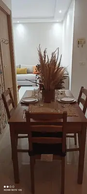 a dining room table with chairs and a table with a plant on it at Cosy Appartement piscine view Magic house Mansouria in Mansouria