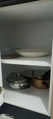 a shelf with plates and pans in a cabinet at Cosy Appartement piscine view Magic house Mansouria in Mansouria