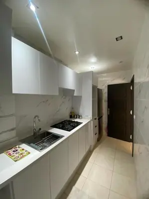 a kitchen with white cabinets and a black door at Well-equipped luxury apartment in Temara